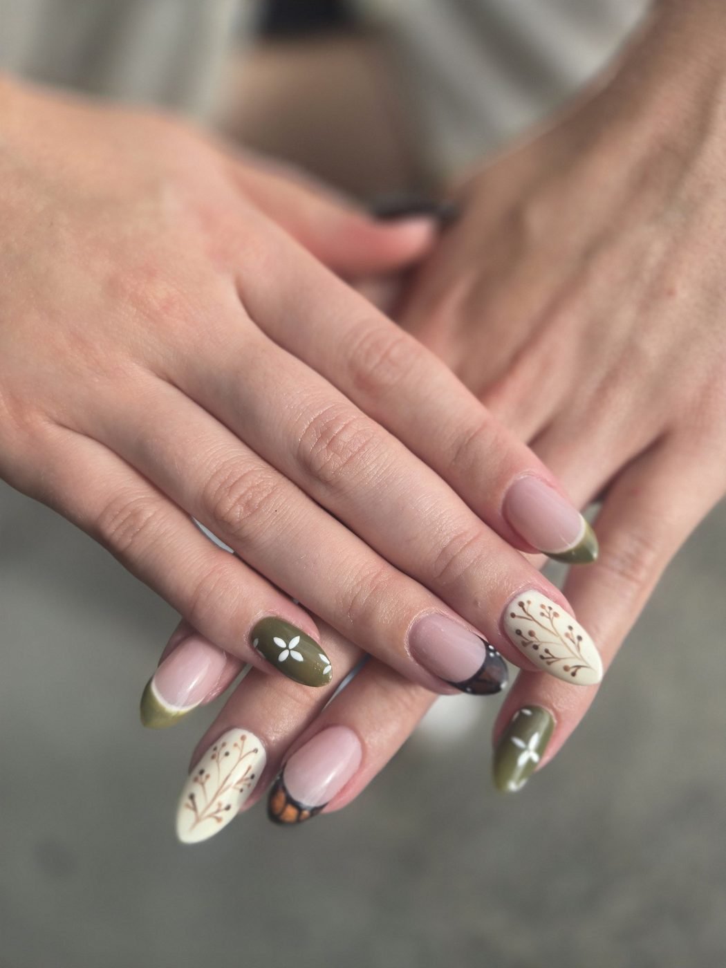 Almond nails in olive, cream and nude with hand-painted botanical sprigs and tiny flowers