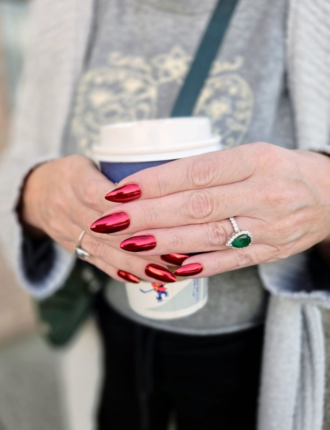 Glossy red chrome almond nails, hands holding a coffee cup